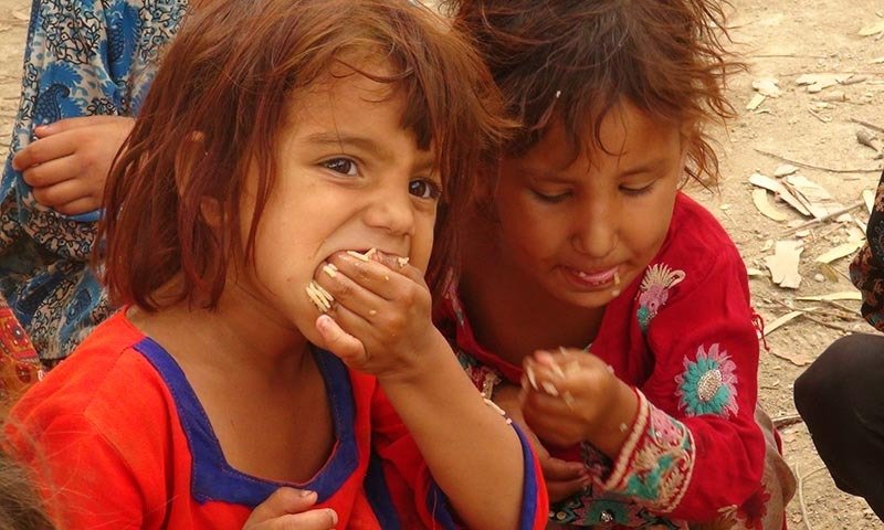 Two young girls eating food provided through our food assistance programme
